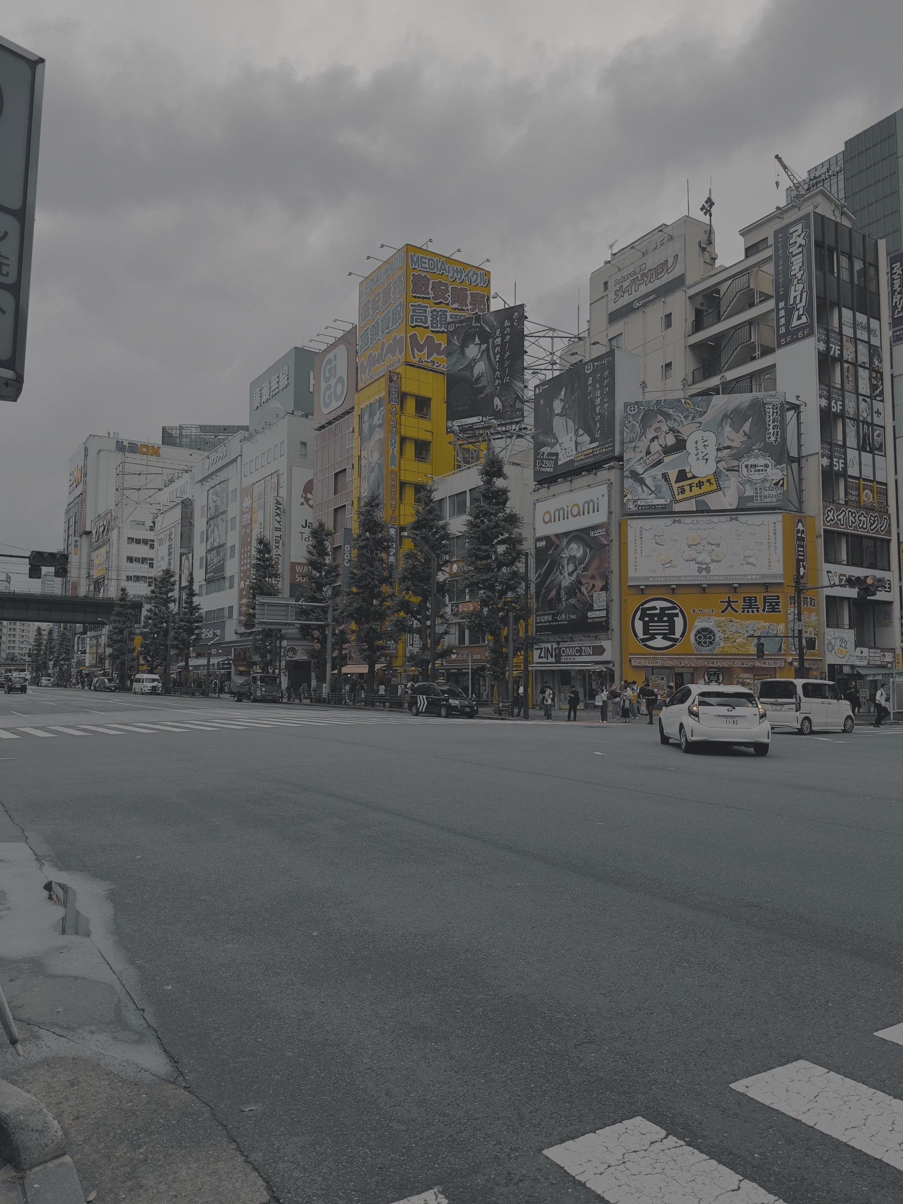 A city intersection framed by colorful signs and tall buildings.